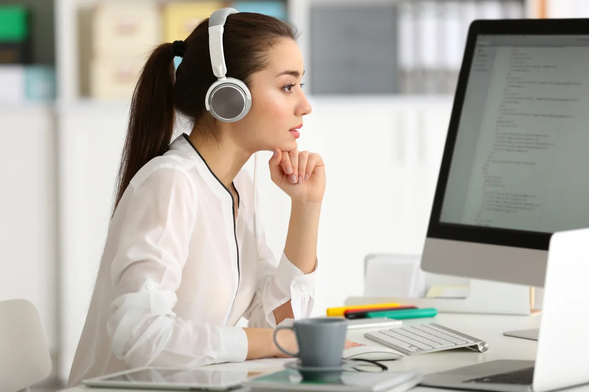 A transcriptionist wearing headphones works at a computer